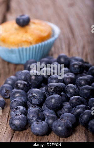 Un muffin ai mirtilli e molti mirtilli sul vecchio tavolo in legno Foto Stock