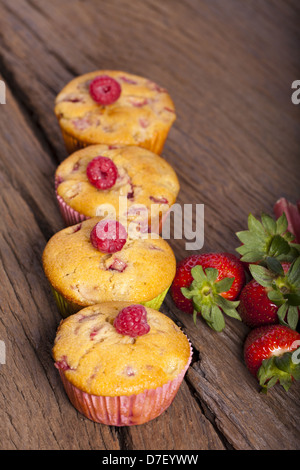 Quattro frutta intera muffin in fila su una vecchia scheda di legno Foto Stock