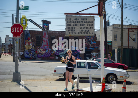 Una donna cammina un cane per i murales che la grazia gli edifici nel cosiddetto 'cinque punti di Bushwick' Foto Stock