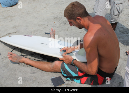 Una scena da Spice Coast India surf e SUP Championship Kovalam Beach, India. Concorrente riparando il suo Navigare pensione Foto Stock