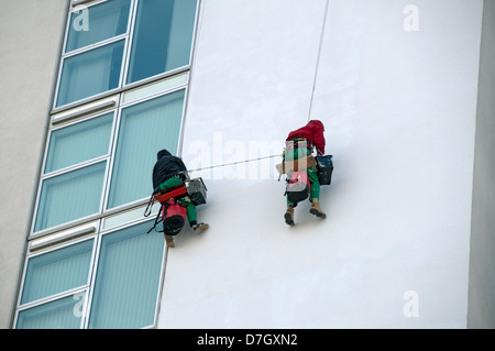 La pittura di un blocco di appartamenti con corda industriale tecniche di accesso. Salford Quays, Salford, Manchester, Inghilterra, Regno Unito Foto Stock