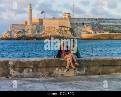 Un misto di etnia matura in amore sit strettamente insieme, intrecciate, sulla parete del Malecón a l'Avana, Cuba. Foto Stock