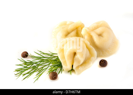 Canederli di carne (pelmeni) con aneto (finocchio) e pepe isolato su uno sfondo bianco, vicino. Foto Stock