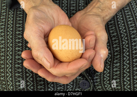 Un uovo in anziani le mani. Foto Stock