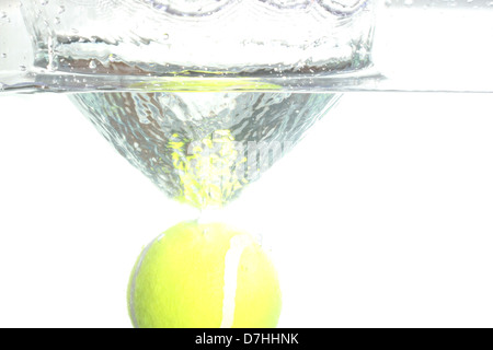 Palla da tennis di caduta in acqua, provocando la diffusione dell'acqua. Foto Stock