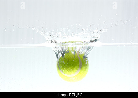 Palla da tennis di caduta in acqua, provocando la diffusione dell'acqua. Foto Stock