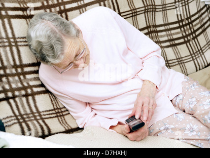 Donna anziana utilizzando un settore specializzato in grande pulsante telefono chiamando il 111 in situazioni di non emergenza consulenza medica helpline a causa di malessere Foto Stock