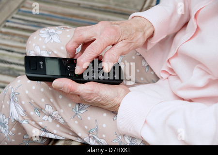 Donna anziana utilizzando un settore specializzato in grande pulsante telefono chiamando il 111 in situazioni di non emergenza consulenza medica helpline a causa di malessere Foto Stock