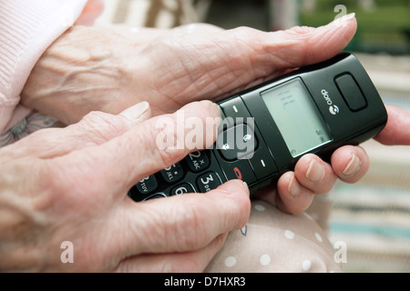 Donna anziana utilizzando un settore specializzato in grande pulsante telefono chiamando il 111 in situazioni di non emergenza consulenza medica helpline a causa di malessere Foto Stock