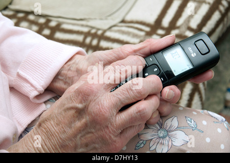 Donna anziana utilizzando un settore specializzato in grande pulsante telefono chiamando il 111 in situazioni di non emergenza consulenza medica helpline a causa di malessere Foto Stock