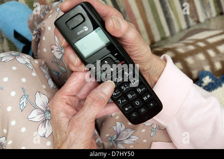 Donna anziana utilizzando un settore specializzato in grande pulsante telefono chiamando il 111 in situazioni di non emergenza consulenza medica helpline a causa di malessere Foto Stock