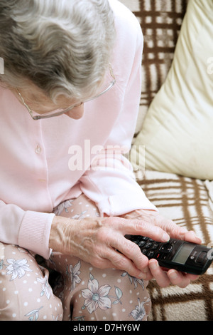 Donna anziana utilizzando un settore specializzato in grande pulsante telefono chiamando il 111 in situazioni di non emergenza consulenza medica helpline a causa di malessere Foto Stock