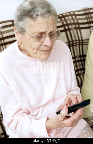 Donna anziana utilizzando un settore specializzato in grande pulsante telefono chiamando il 111 in situazioni di non emergenza consulenza medica helpline a causa di malessere Foto Stock