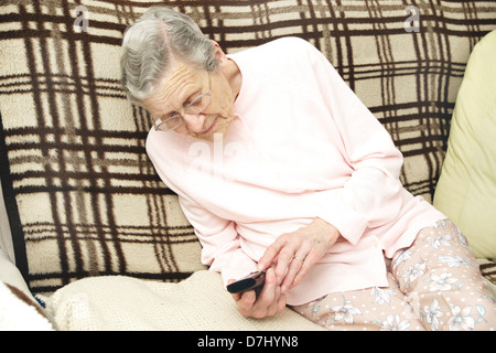 Donna anziana utilizzando un settore specializzato in grande pulsante telefono chiamando il 111 in situazioni di non emergenza consulenza medica helpline a causa di malessere Foto Stock