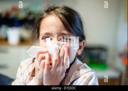 Bambina soffia il naso con un fazzoletto Foto Stock