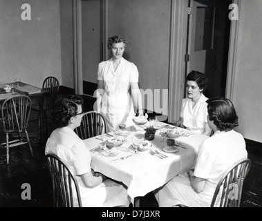 Una fotografia storica degli archivi OSU che mostra un corso di Home Economics Food Management. L'immagine riflette le pratiche educative nei primi anni della formazione in economia domestica, con gli studenti che imparano la preparazione del cibo e le capacità di gestione. Foto Stock