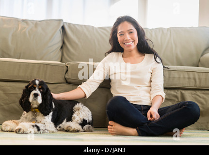 Giovane donna con il cane in livingroom Foto Stock