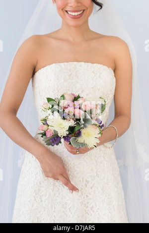 Sposa in velo holding bouquet e dita incrociate Foto Stock