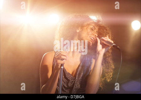 Giovane donna cantare in Spotlight Foto Stock