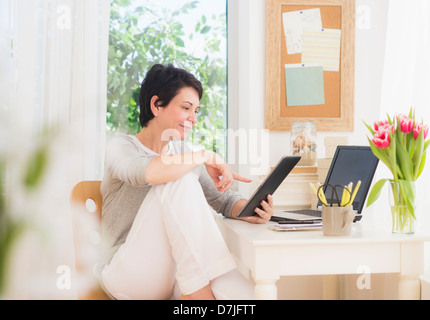 Donna matura con tavoletta digitale e il computer portatile Foto Stock