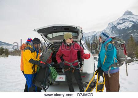 Gruppo di amici preparando per escursioni con le racchette da neve in montagna