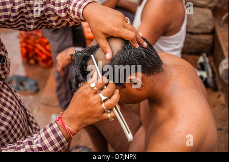 Rasatura dell'uomo capelli come parte di indù rituale religioso sulla morte di un membro della famiglia a Varanasi, Uttar Pradesh, India. Foto Stock