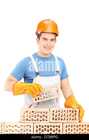 Maschio lavoratore manuale di costruzione di un muro di mattoni isolati su sfondo bianco Foto Stock