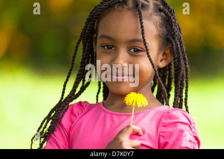 Outdoor ritratto di un simpatico giovane nero ragazza con un fiore di tarassaco - popolo africano Foto Stock