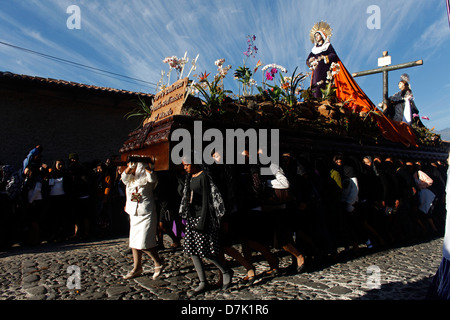 Le donne vestite con abiti tradizionali portano un trono con un immagine della Vergine Maria durante la Semana Santa in Antigua Guatemala Foto Stock