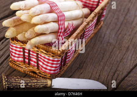 Asparagi bianchi legate con un nastro di tessuto in una cesta e un coltello con impugnatura in corno di bue Foto Stock