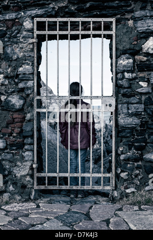 Una ragazza dietro un traliccio porta, guardando verso il mare Foto Stock