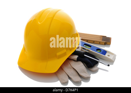 Un giallo appaltatori elmetto su guanti da lavoro e strumenti. Formato orizzontale su bianco con la riflessione. Foto Stock