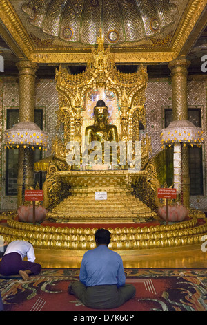Gli uomini la preghiera al Buddha dorato alla Pagoda Boatataung, Yangon, Myanmar Foto Stock