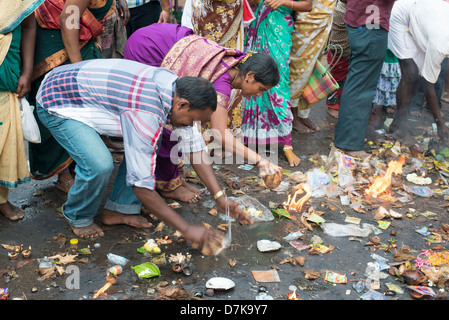 Un indù devoto interruzioni aperta una noce di cocco come offerta al tempio Arunachaleswara a Tiruvannamalai, Tamil Nadu, India Foto Stock