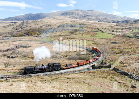 Una locomotiva a vapore tirando un treno merci sul Welsh Highland linea ferroviaria, Galles Foto Stock