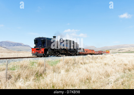 Una locomotiva a vapore tirando un treno merci sul Welsh Highland linea ferroviaria, Galles Foto Stock