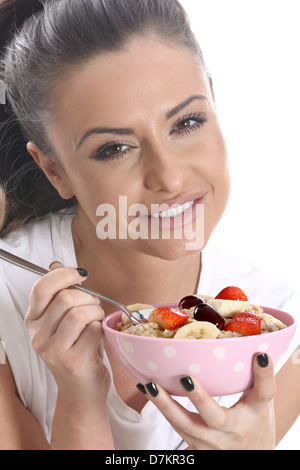 Modello rilasciato. giovane donna di mangiare il porridge e frutta fresca Foto Stock