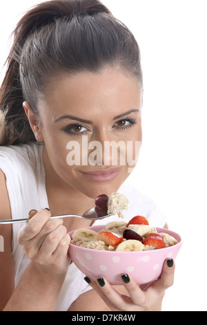 Modello rilasciato. giovane donna di mangiare il porridge e frutta fresca Foto Stock