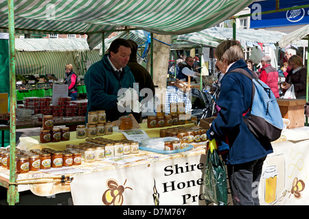 Donna che fa shopping che guarda i barattoli di miele locale in vendita nella banchina del mercato nel centro della città di York North Yorkshire Inghilterra Regno Unito Regno Unito Gran Bretagna Foto Stock