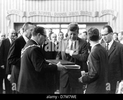 Il presidente statunitense John Fitzgerald Kennedy (m) riceve un regalo di benvenuto, un libro illustrato di circa un giro sul Reno e i record con le sinfonie di Beethoven, da Lord Mayor Theo Burauen (l, con catena di ufficio) presso il municipio di Colonia poco dopo il suo arrivo all'aeroporto di Colonia/Bonn il 23 giugno 1963. Il presidente è stato in visita nella Repubblica federale per quattro giorni. Foto Stock