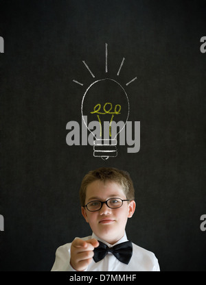 L'istruzione deve pensare boy vestito come uomo d affari con la brillante idea di chalk lampadina di sfondo su sfondo blackboard Foto Stock