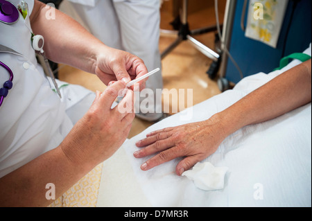 L'infermiera la preparazione di un paziente per una linea IV Foto Stock