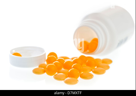 Giallo pillole sparse nella parte anteriore della parte in plastica bianca jar. Foto Stock