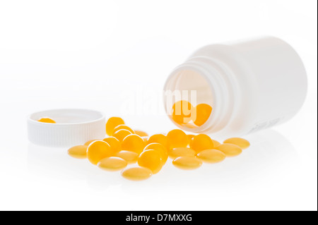 Giallo pillole sparse nella parte anteriore della parte in plastica bianca jar. Foto Stock