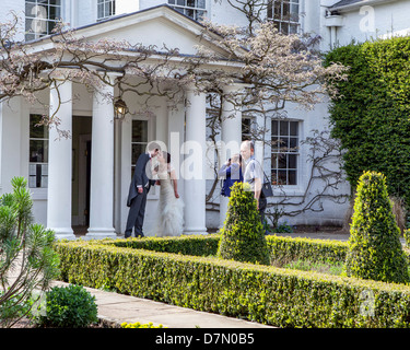 Una coppia di sposi posa per fotografie presso lo sportello anteriore di Pembroke House, una dimora georgiana a Richmond Park Foto Stock