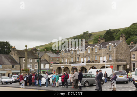 Una lunga ma ordinata coda di bus in luogo di mercato a Settle, North Yorkshire. La coda è formato per la maggior parte delle persone anziane. Foto Stock
