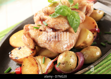 Ali di pollo e le patate cosparso di erba cipollina Foto Stock