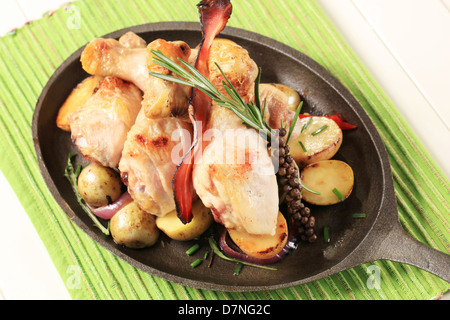 Cosce di pollo disossate di pollo e le patate su una padella in ghisa Foto Stock