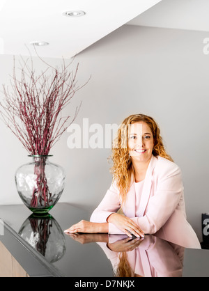 Receptionist in piedi presso il banco di ricevimento in ufficio Foto Stock