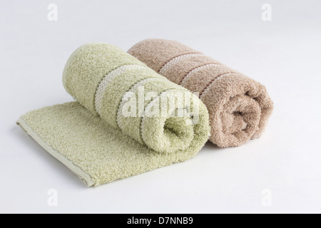 Verde e marrone asciugamani arrotolato su sfondo bianco Foto Stock